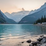 “Lake Louise shoreline with mountains partially obscured by smoky haze in the distance, suggesting reduced visibility from poor air quality.”