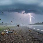 Dark storm clouds with rain and distant lightning over a rural Alberta roadside near Yellowhead County, representing severe thunderstorm conditions.