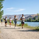 People walking and jogging on a Kamloops outdoor trail under a clear blue sky, suggesting good outdoor air quality.
