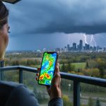 “A person in Spruce Grove holding a smartphone while storm clouds gather in the sky, suggesting local radar monitoring for severe weather.”